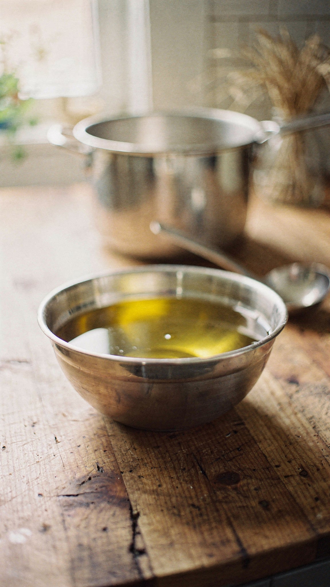 Rendered beef tallow for skin straining through cheesecloth into a stainless steel bowl.