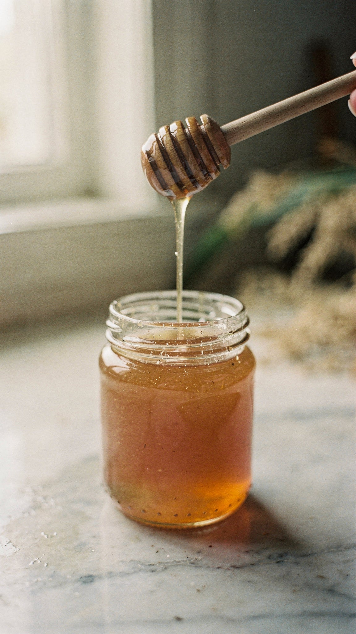 Raw unfiltered honey for skin, cloudy and crystallising in an open glass jar.