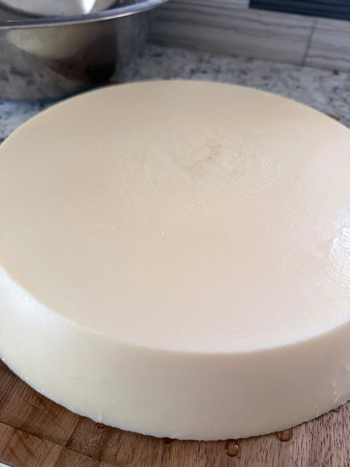 Rendered grass-fed beef tallow in a stainless bowl beside a jar of body butter.