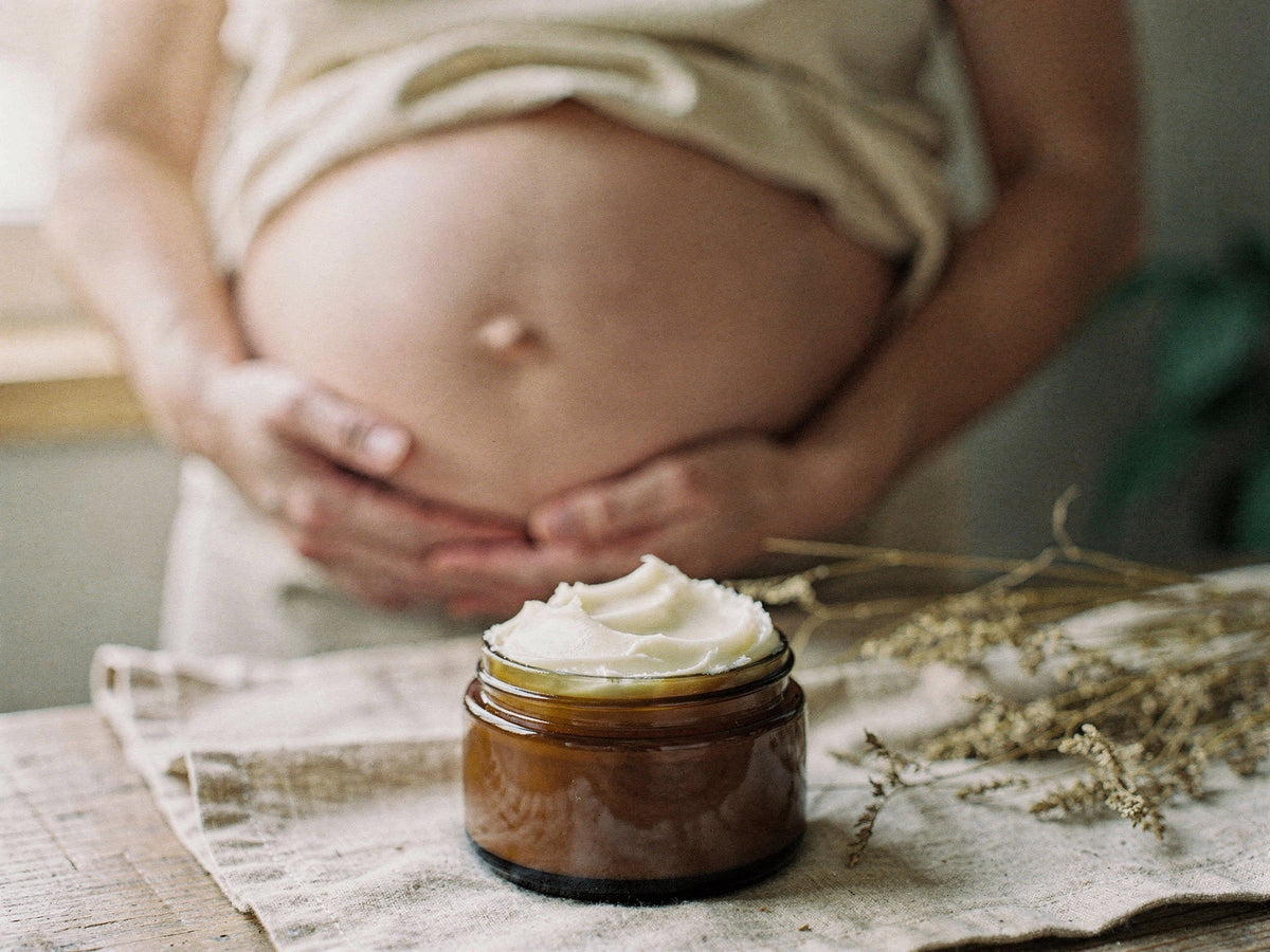 Whipped tallow body butter smoothed onto a pregnant belly, mid-application.