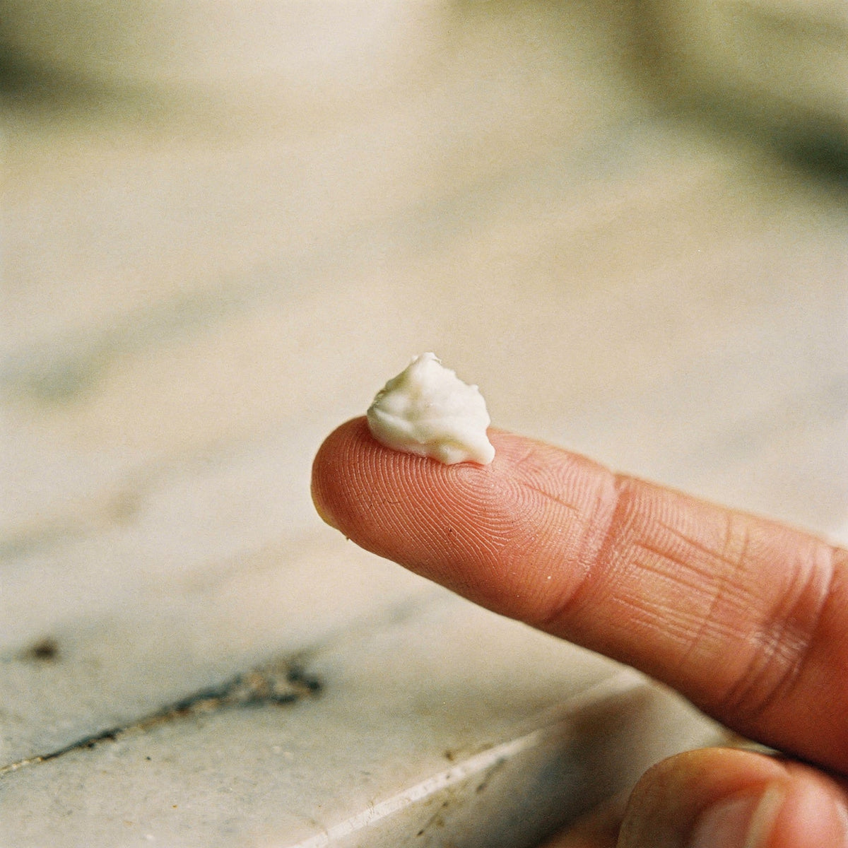 A rice-grain dab of tallow balm on a fingertip, the amount for the eye area.